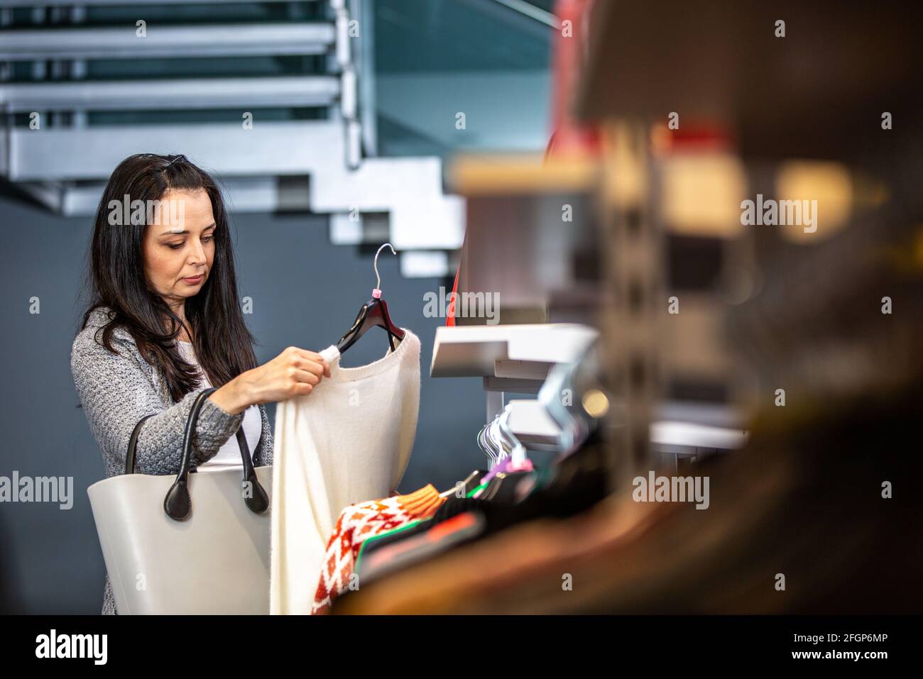 Donna giovane graziosa che fa lo shopping o che compra alcuni vestiti a. il negozio o boutique Foto Stock