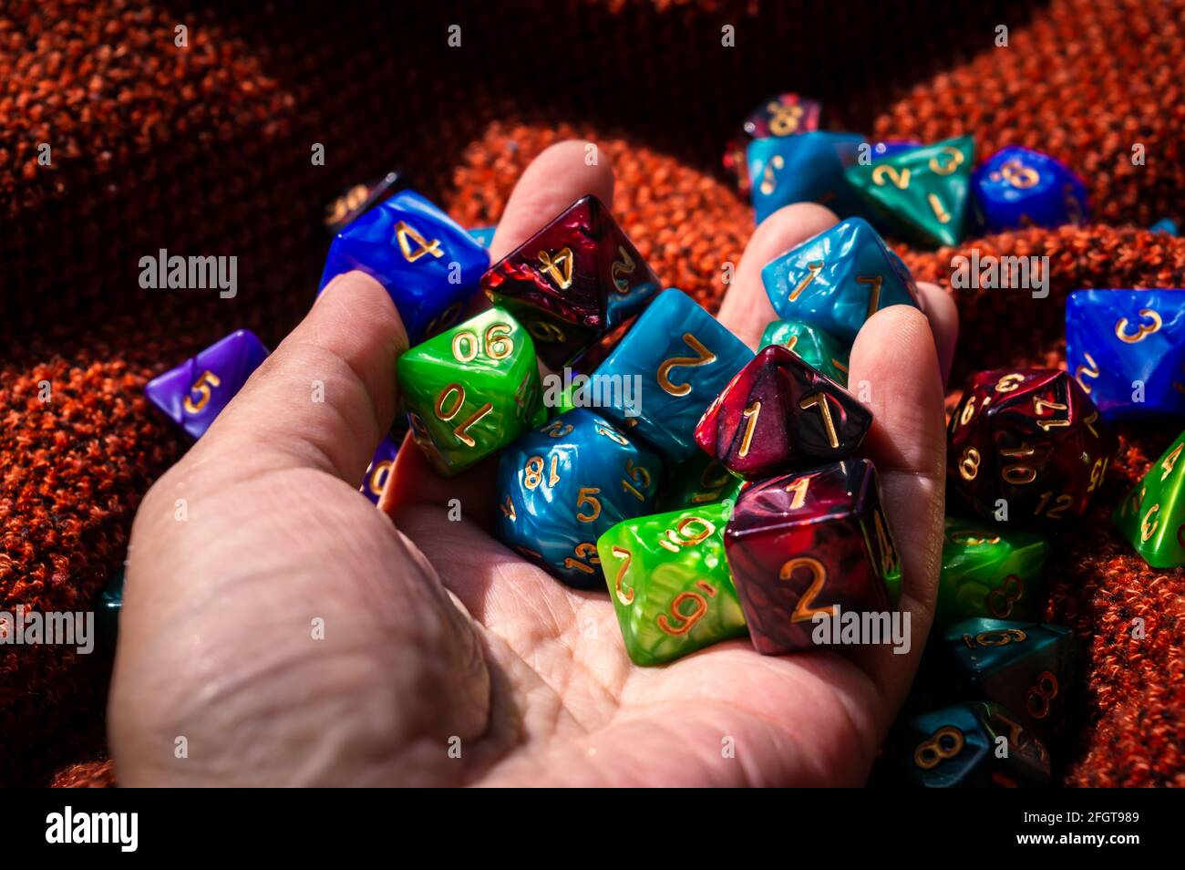 Un'immagine di una mano piena di dadi di gioco RPG al caldo sole del pomeriggio Foto Stock