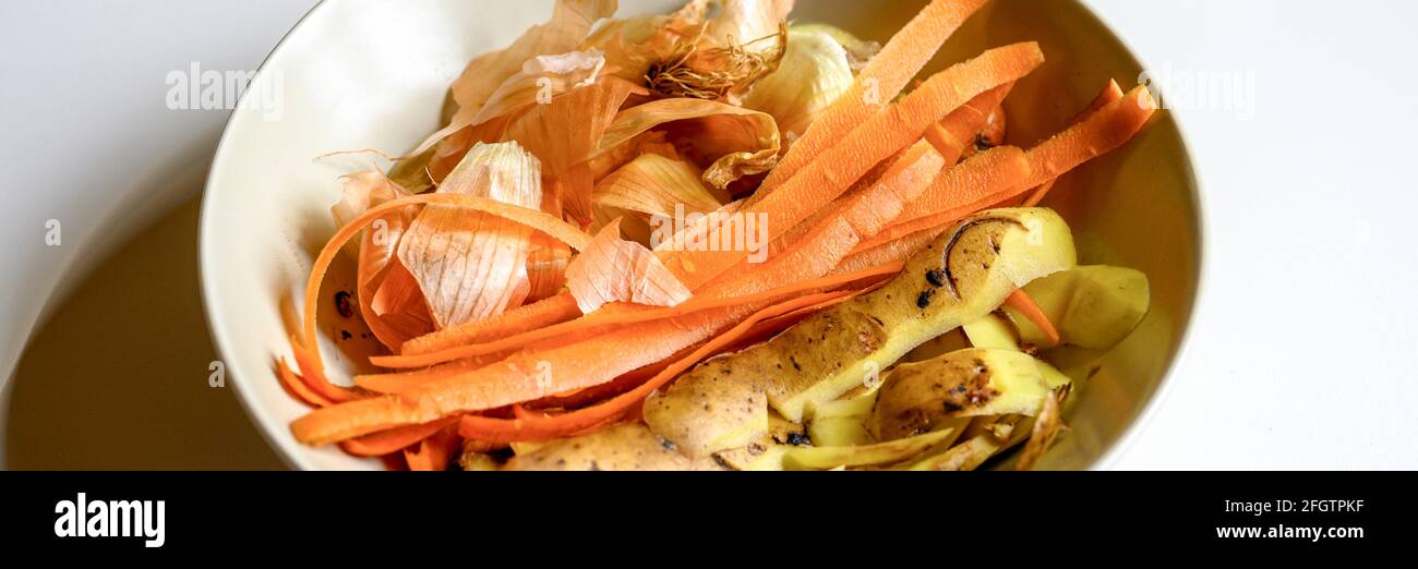 rifiuti alimentari da cucina domestica, pulizia da verdure cipolle patate e carote in un piatto su uno sfondo bianco tavola. cernita di casa fo Foto Stock