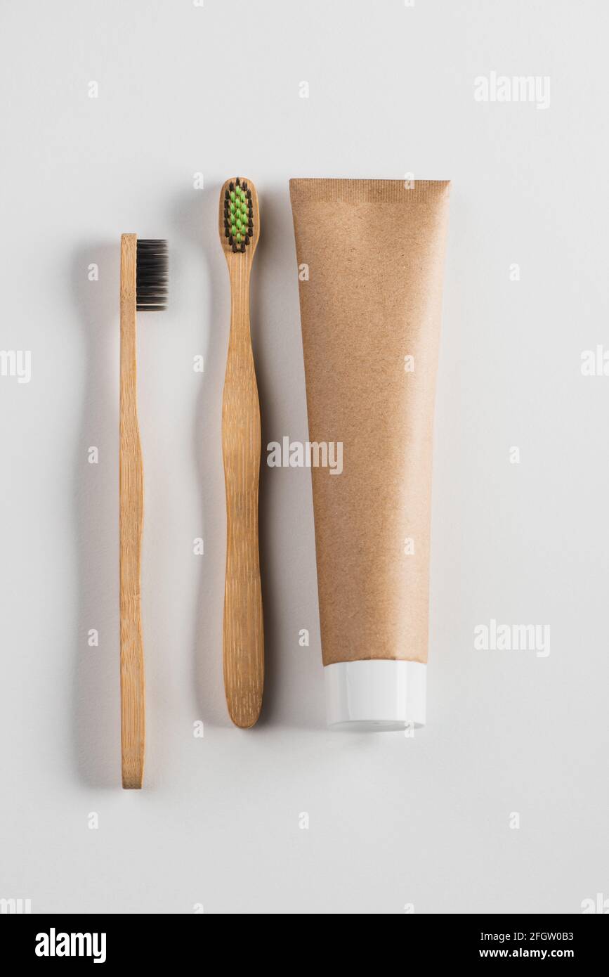 Vista dall'alto su spazzolini da denti in legno e dentifricio su sfondo bianco Foto Stock