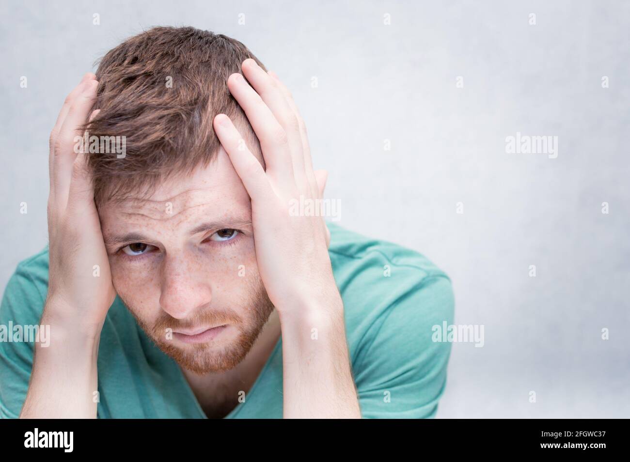 Il giovane tiene le mani sulla testa. Concetto di dolore e dolore Foto Stock