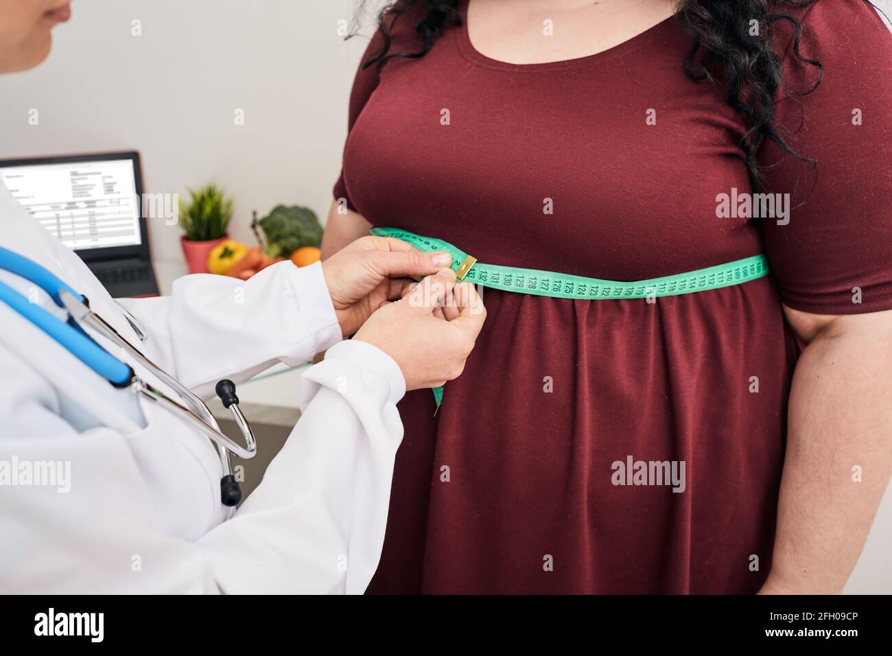 Obesità, peso malsano. Nutrizionista ispezionando la vita di una donna usando un metro a nastro per prescrivere una dieta di perdita di peso Foto Stock