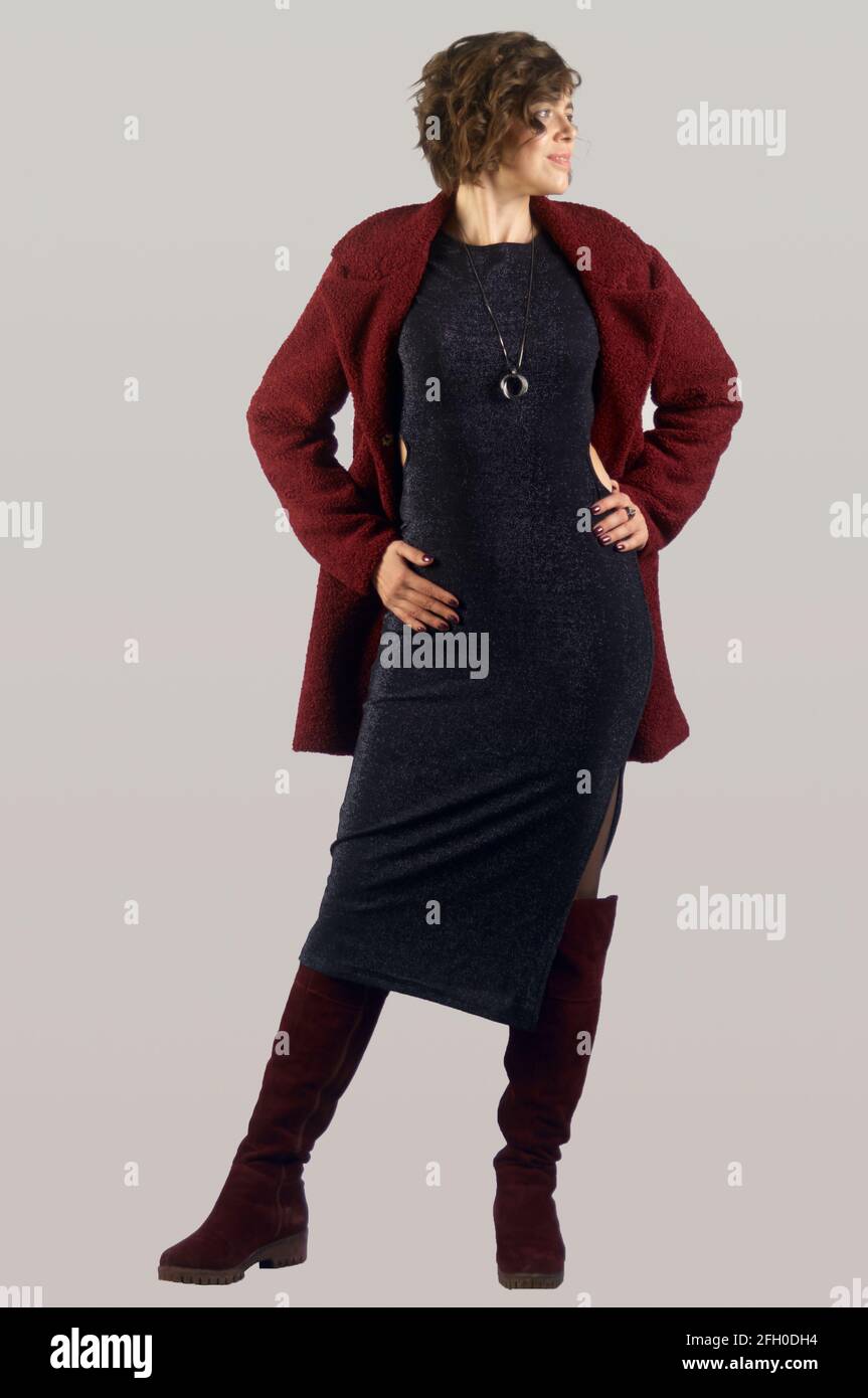 Ritratto a lunghezza intera di donna adulta vestito in abito nero, giacca  rossa e stivali rossi a ginocchio su sfondo grigio Foto stock - Alamy