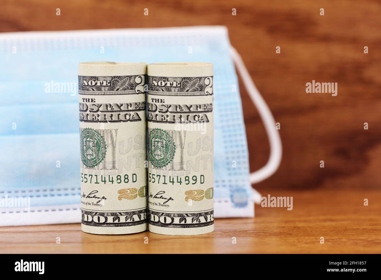 La valuta americana messa con maschera medica è un'immagine concettuale simbolica degli investimenti finanziari in guerra contro Covid 19. Foto Stock