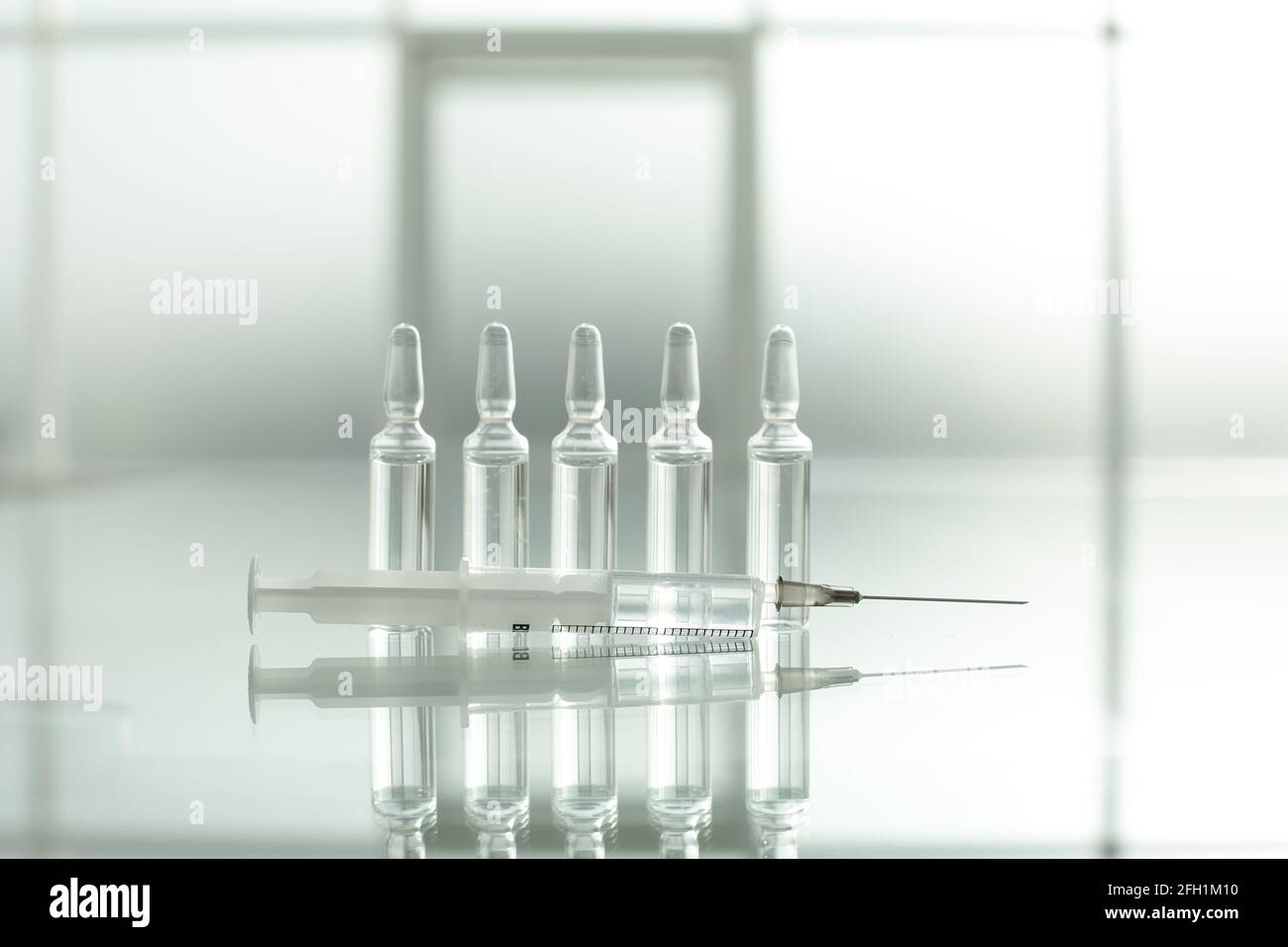 Flaconcini e siringa di medicinale su un tavolo di vetro Foto Stock