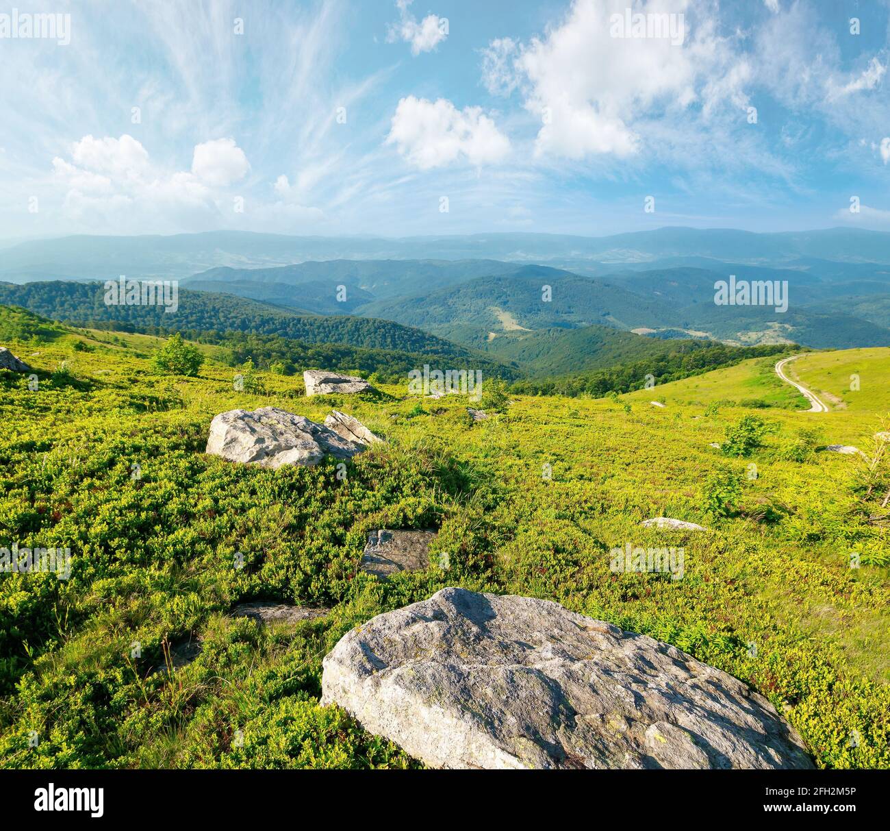 paesaggio montano estivo con pietre sulla collina. splendida vista sulla valle lontana in una mattinata soleggiata. nuvole soffici sopra l'orizzonte Foto Stock