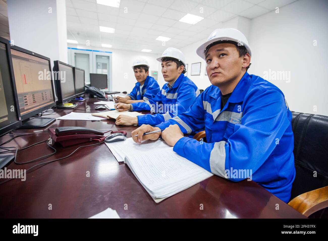 Centrale idroelettrica Moinak, sala di controllo. Tre operatori asiatici che sovrintende ai processi. Uomo giusto in primo piano. Foto Stock