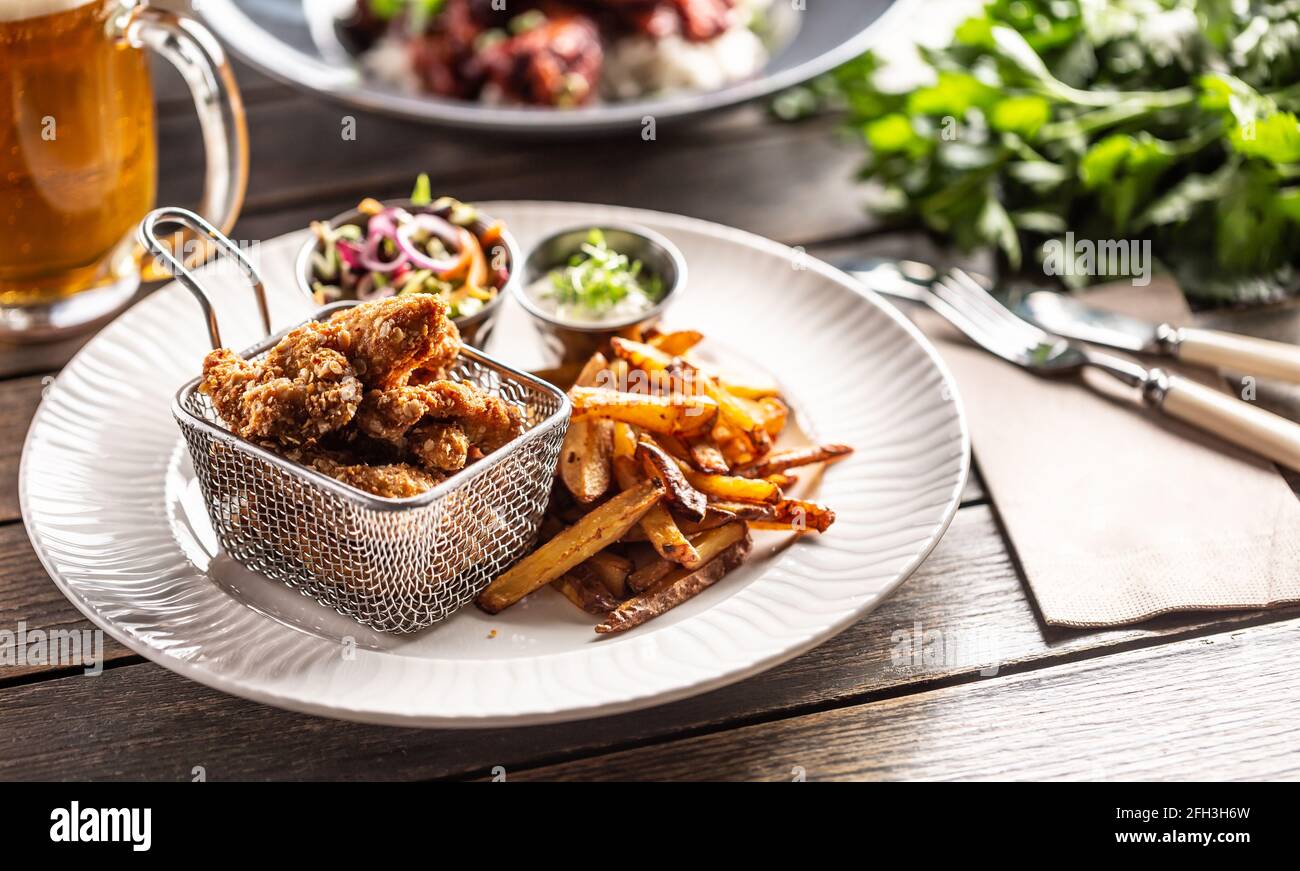 Ali di pollo fritte croccanti con patatine, salsa e insalata serviti su un tavolo. Foto Stock