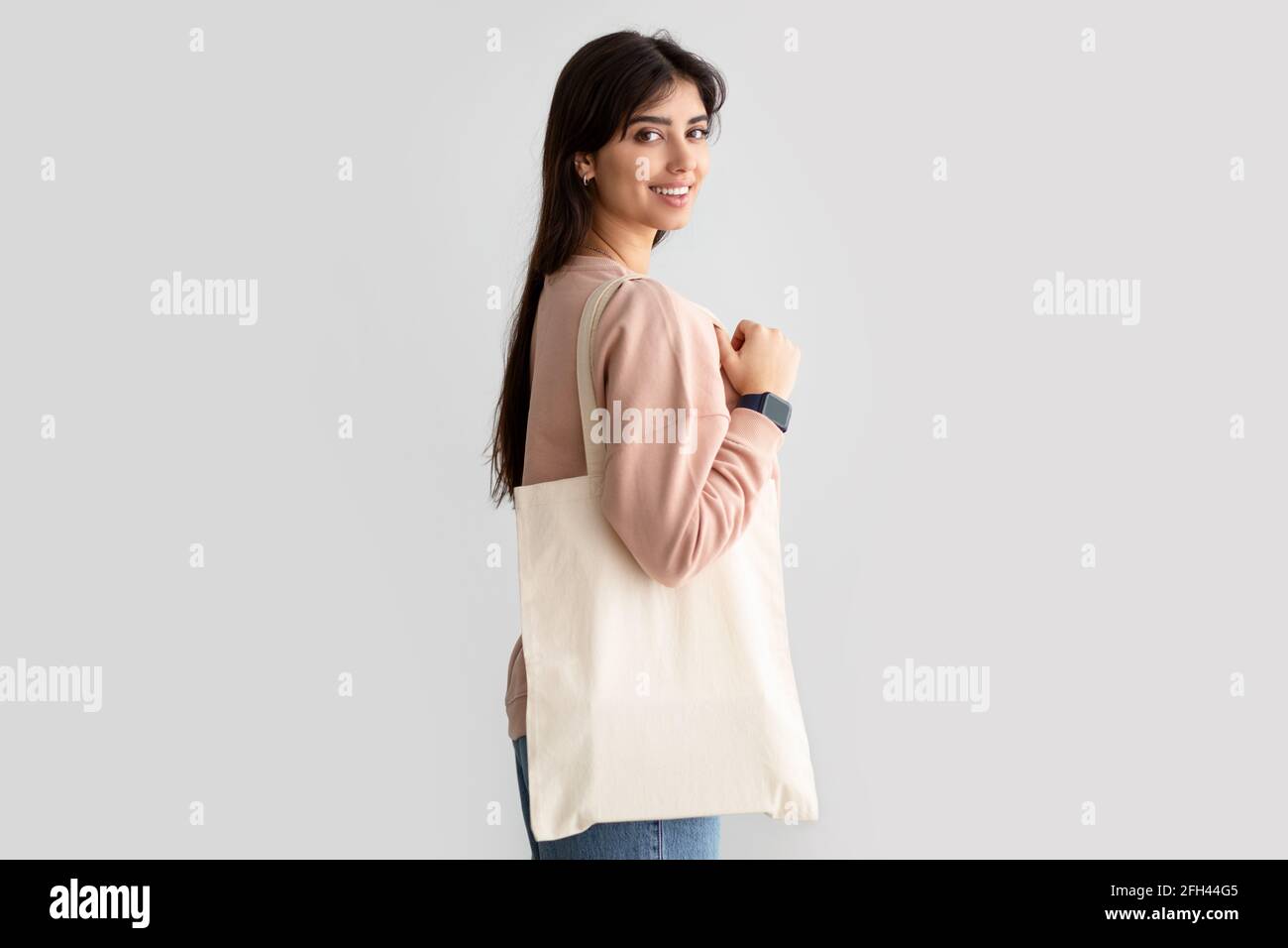 Ritratto di donna sorridente in piedi con borsa tote in tela bianca Foto Stock