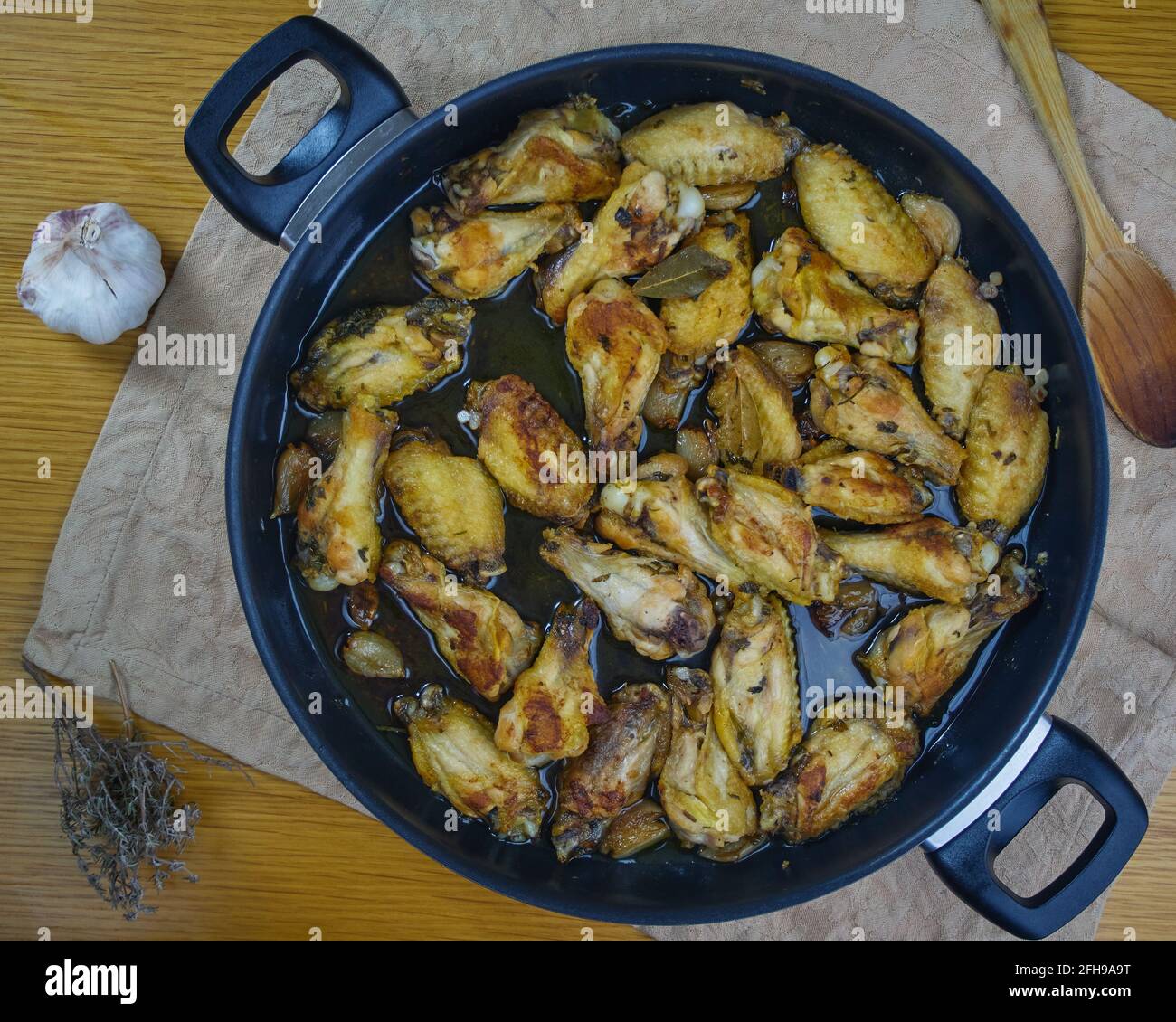Ali di pollo all'aglio (Pollo al ajillo). Piatto di tapas spagnole in padella su un tovagliolo decorato con i suoi ingredienti. Vista dall'alto Foto Stock