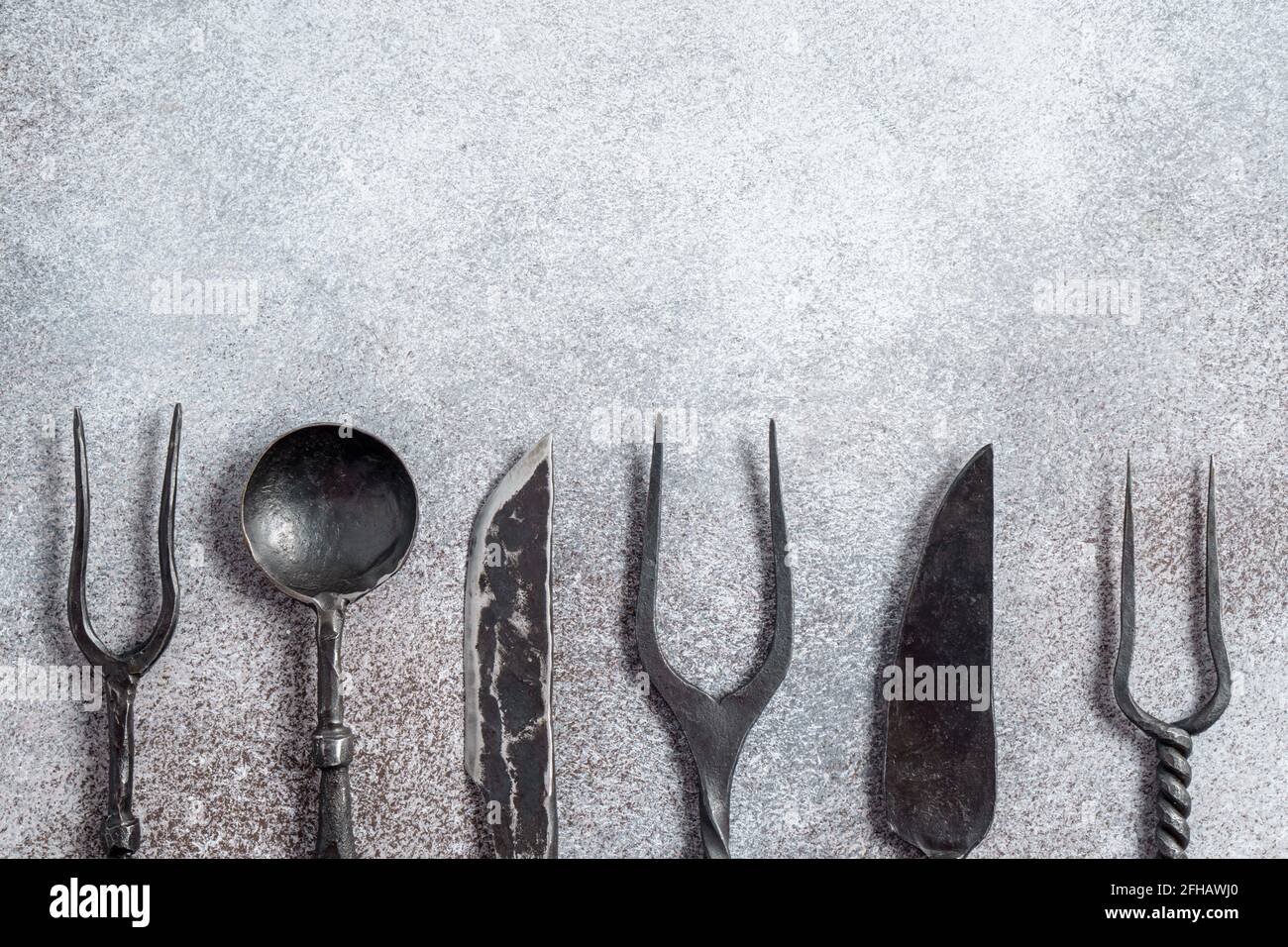 Cucchiaio e coltello per forcelle vintage su cemento con spazio per la copia. Concetto di cibo locale. Foto Stock