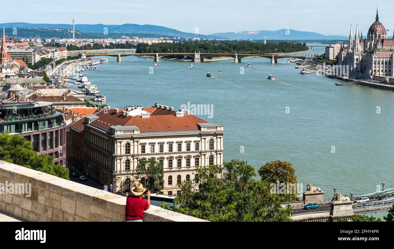 Budapest, Ungheria - 11 agosto 2019: Uomo turistico con cappello che prende foto del Parlamento di Budapest dal lato di Buda Foto Stock