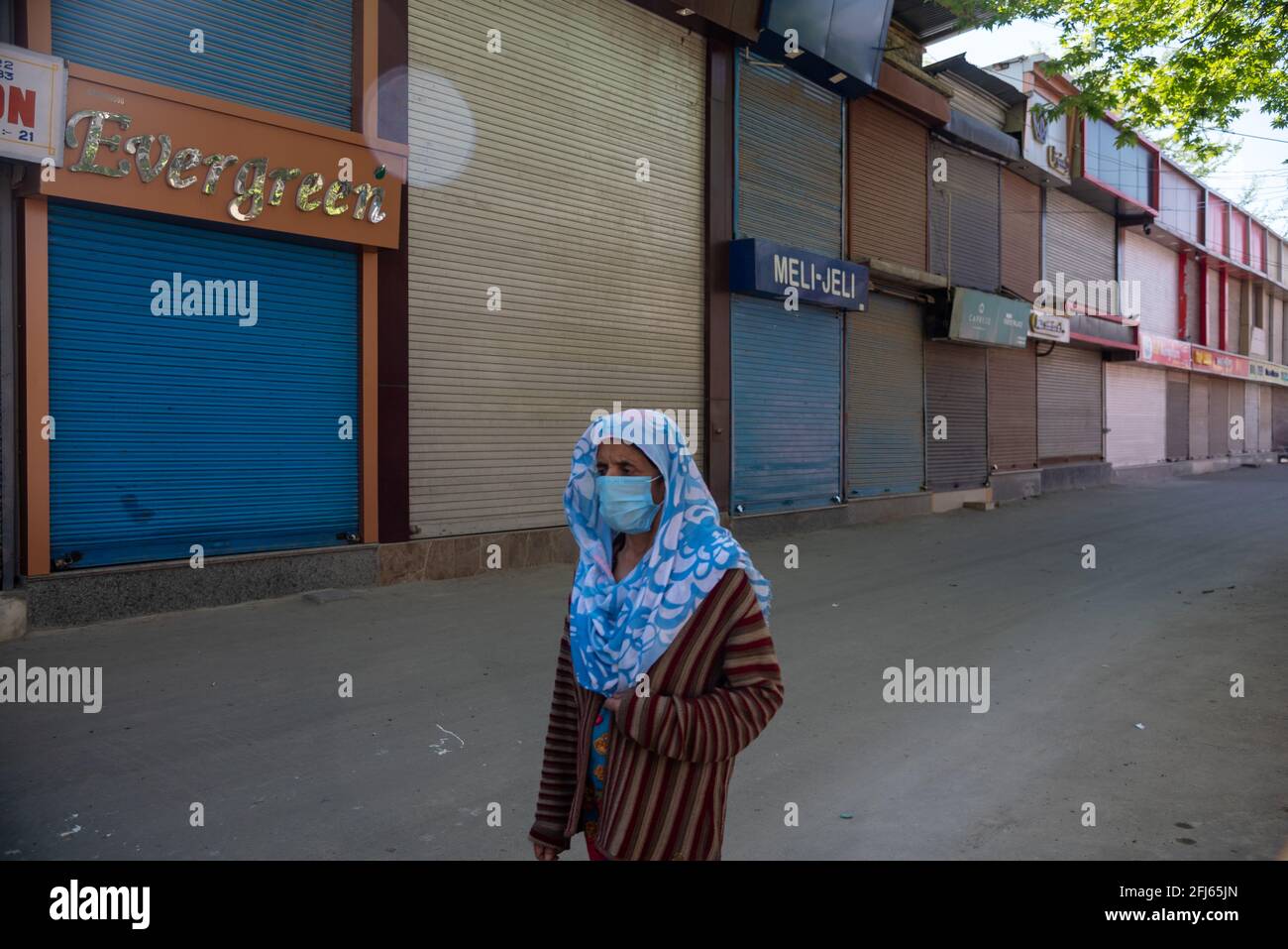 Srinagar, India. 25 Apr 2021. Una donna che indossa una maschera facciale cammina attraverso negozi chiusi durante un coprifuoco di un giorno per frenare la diffusione di COVID-19 in Srinagar.India ha riportato 346,786 nuovi casi di COVID-19 per le 24 ore precedenti, con 2,624 morti, il più alto numero di morti al mondo dal giorno della pandemia iniziata lo scorso anno. Complessivamente, nel paese sono morte quasi 190,000 persone a causa della COVID, mentre oltre 16.6 milioni sono state infettate. (Foto di Idrees Abbas/SOPA Images/Sipa USA) Credit: Sipa USA/Alamy Live News Foto Stock