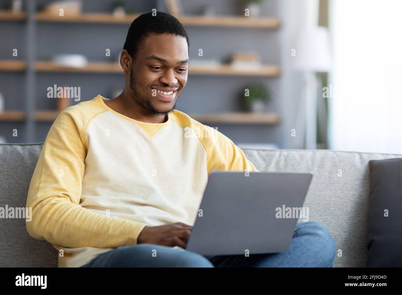 Sorridente afroamericano che partecipa al webinar, utilizzando un notebook Foto Stock
