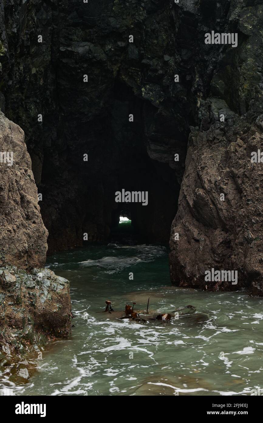 caverna nell'oceano dove l'acqua e le onde passano attraverso di esso. Cooper Coast Irlanda Foto Stock