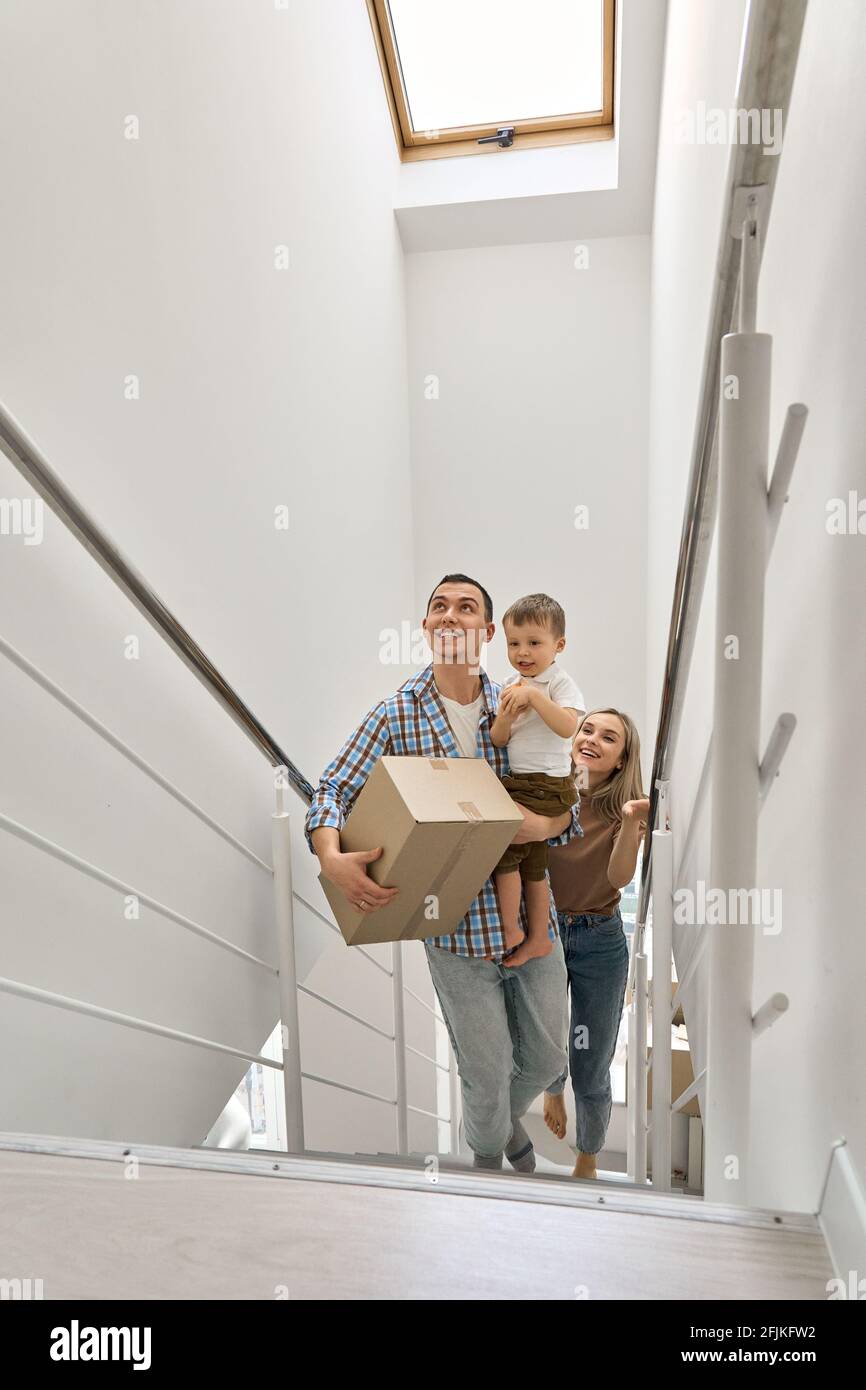 Felice famiglia con bambino figlio scatole di trasporto che salono le scale in nuova casa. Foto Stock