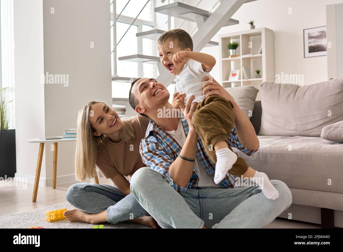Felice giovane coppia di famiglia divertirsi giocando con il figlio carino a casa. Foto Stock