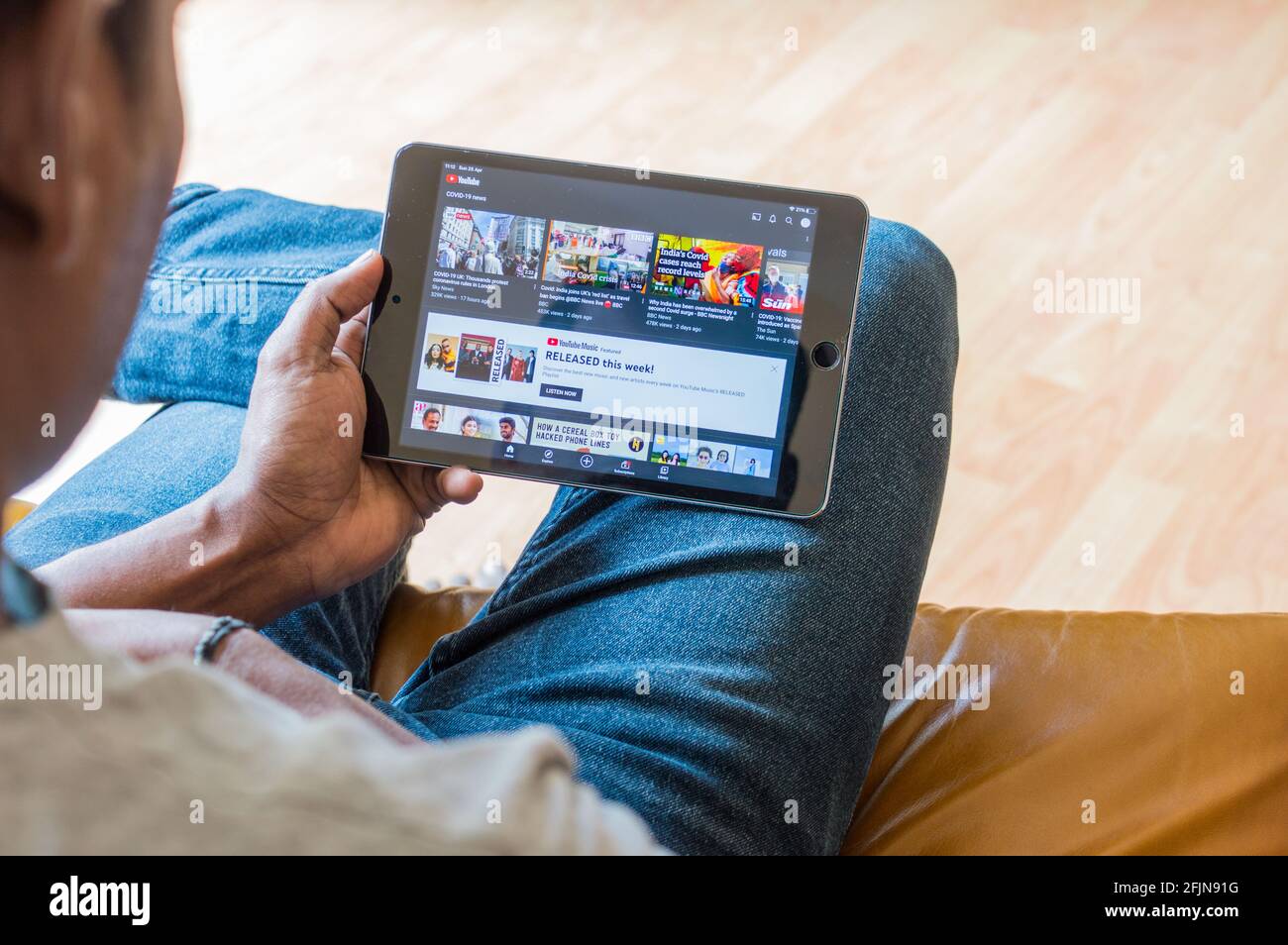 Uomo asiatico adulto seduto sul divano che controlla i video di YouTube su ipad Foto Stock