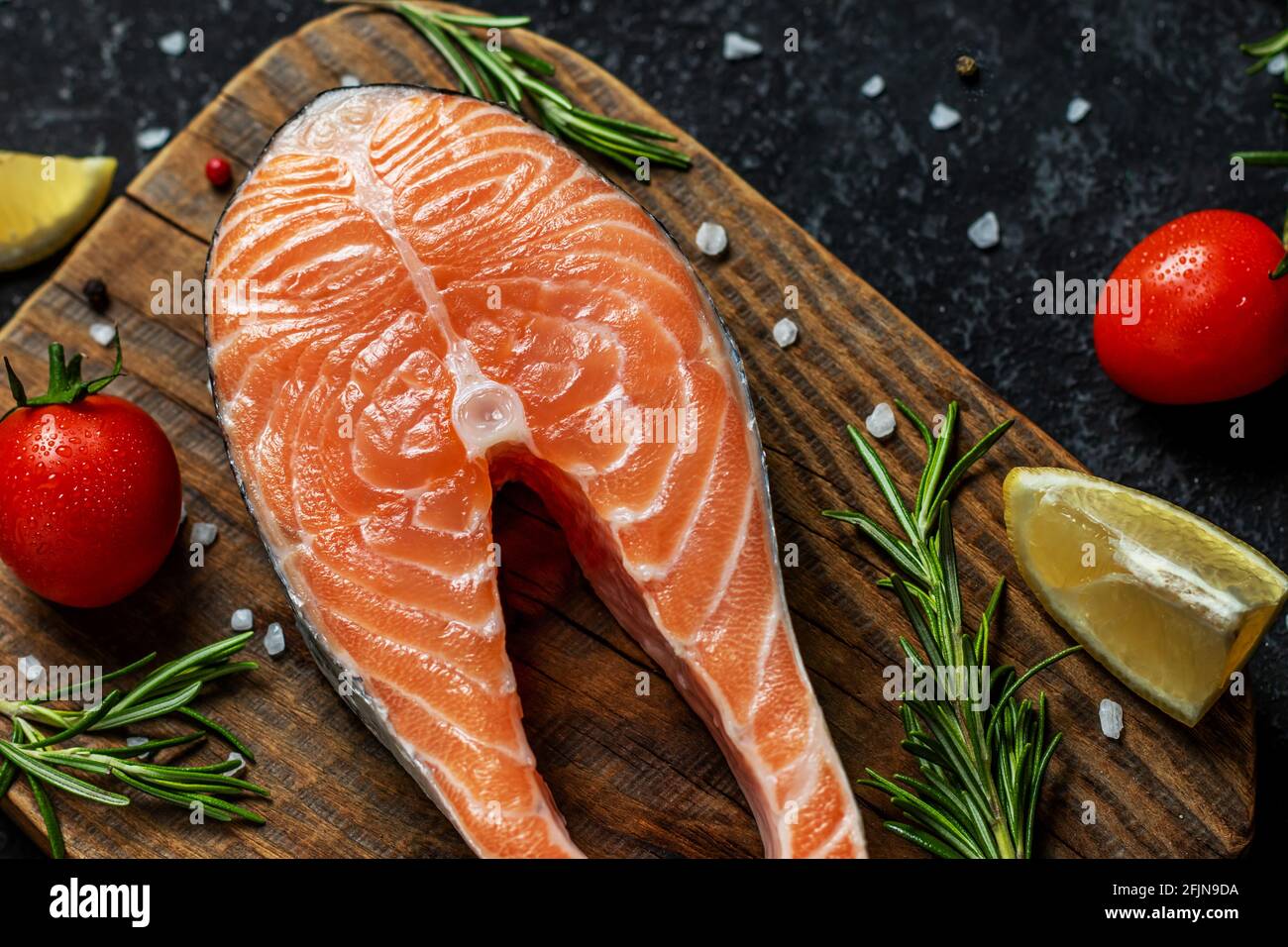 Salmone crudo con spezie e verdure sulla tavola di legno. Foto Stock