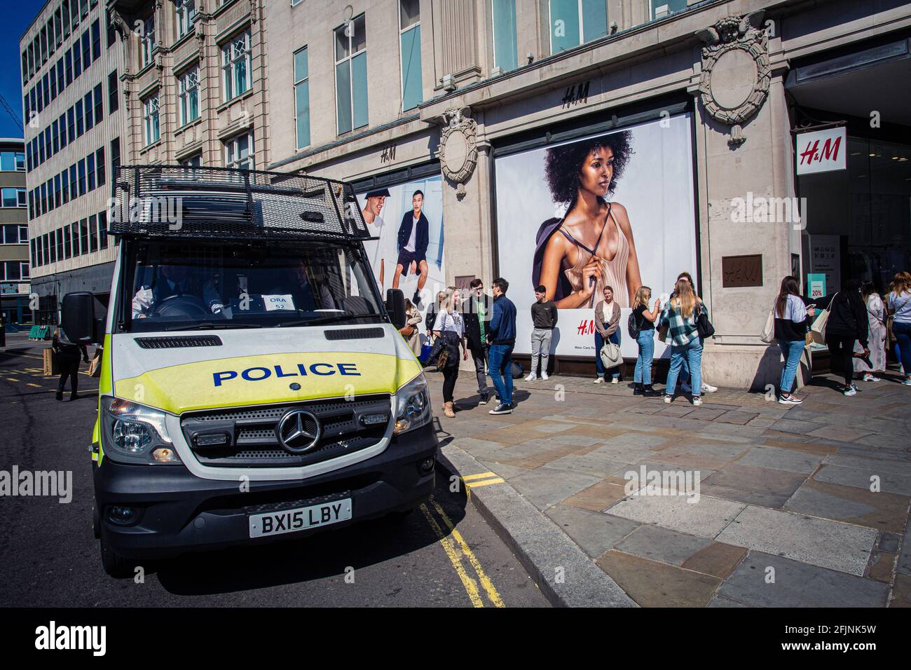 Pulmino di polizia con shopping in coda fuori H&M a Oxford Street London, Regno Unito Foto Stock