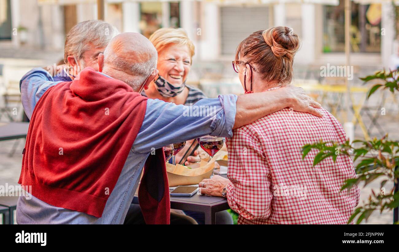 Coppie ritirate che si appendono l'una con l'altra all'esterno bevendo vino Foto Stock