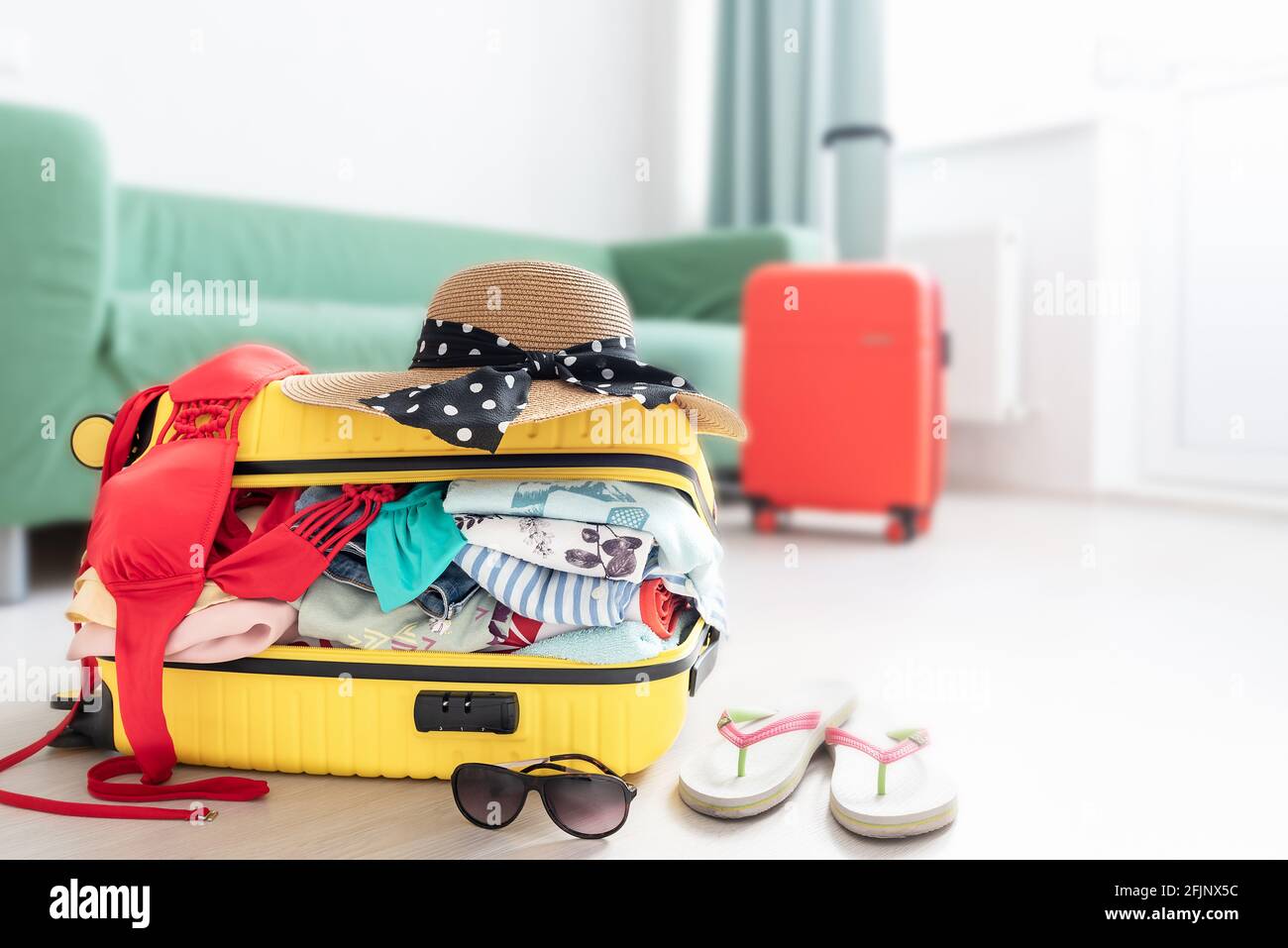 Valigia confezionata in vacanza, Open yellow bagaglio pieno di vestiti in camera Foto Stock