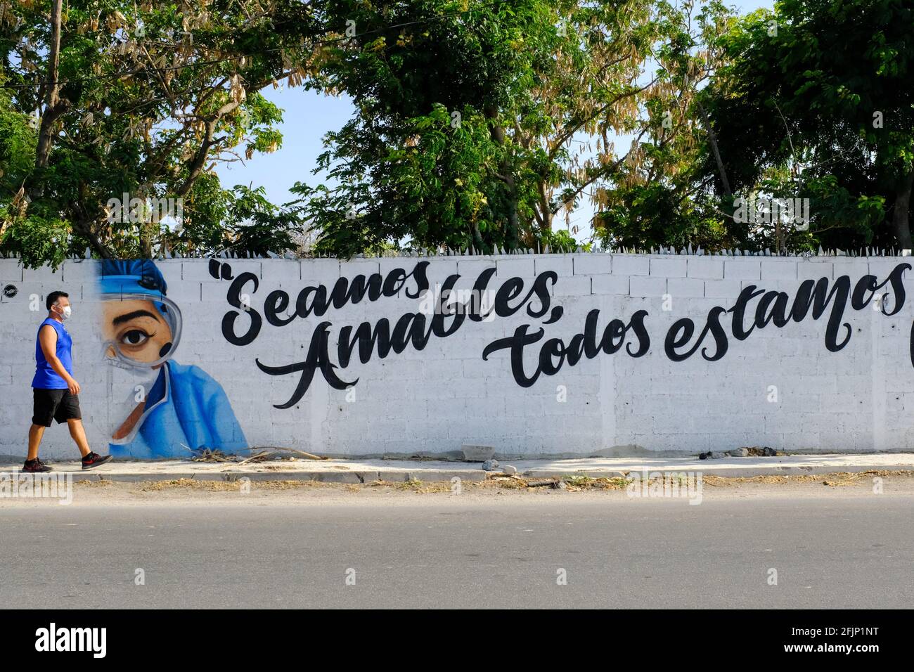 L'uomo che passa di fronte a un murale raffigurante i primi risponditori di Covid-19 ha salutato come eroi nella lotta contro la pandemia, Merida Messico Foto Stock