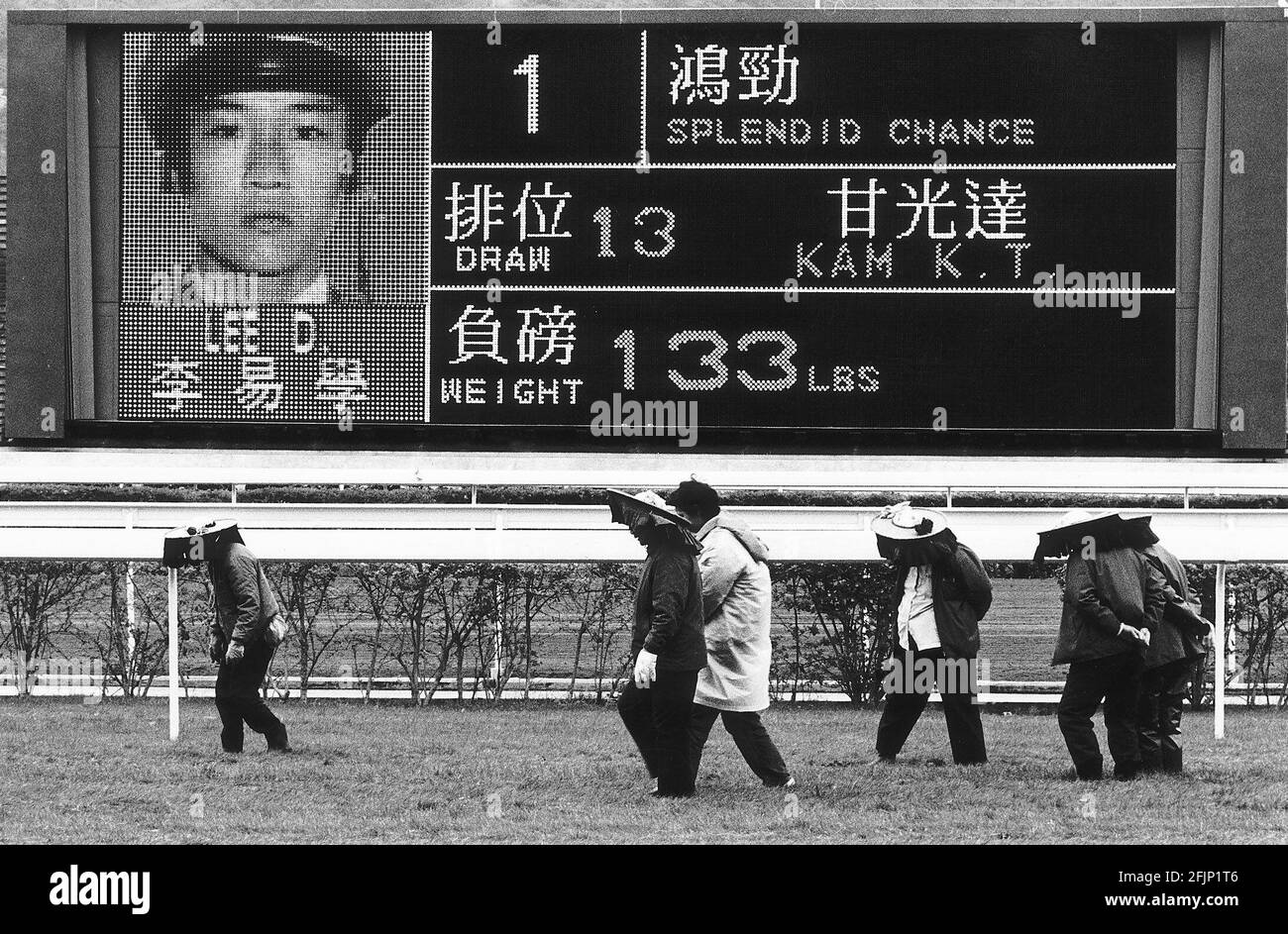 Ippodromo di Sha Tin Hong Kong. I curatori del corso stampano la loro autorità sulla riparazione a terra tra le gare a Sha Tin di fronte alla schermata di visualizzazione dei risultati e degli annunci della gara Foto Stock