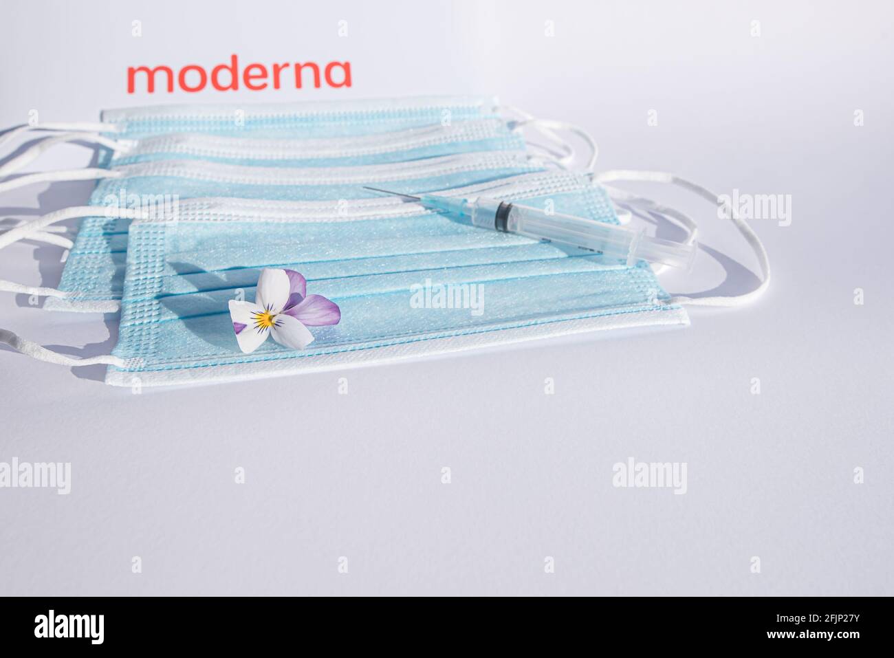 Il logo rosso della moderna con una siringa e una maschera blu su sfondo bianco con spazio per la copia, Danimarca, 25 aprile 2021 Foto Stock