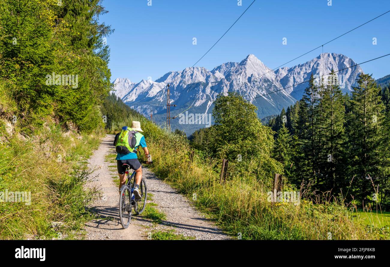 Ciclista in bicicletta con mountain bike, sulla pista ciclabile Via Claudia Augusta, dietro Ehrwalder Sonnenspitze, Ehrwalder Becken, nei pressi di Ehrwald, Tirolo Foto Stock
