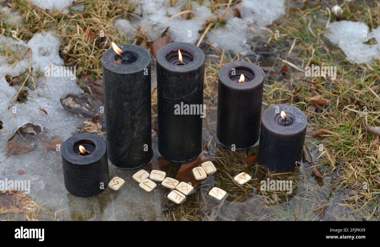 Rituale Wiccan con gruppo di candele nere e rune in acqua. Sfondo esoterico, gotico e occulto, Halloween mistico e wicca concetto all'aperto. Foto Stock