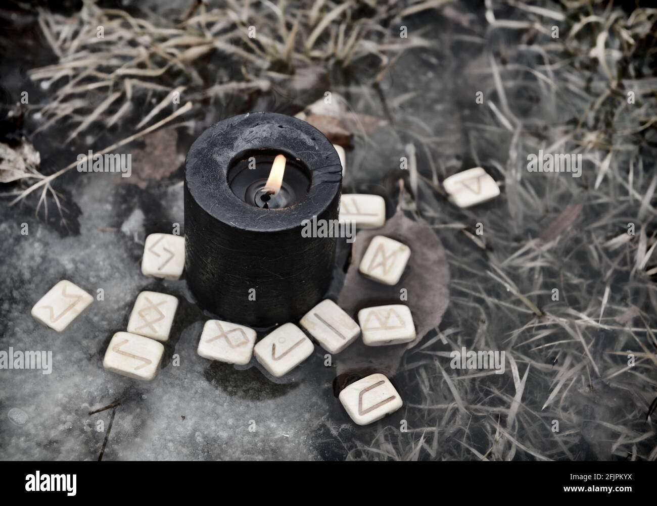 Rituale Wiccan con rune di legno e candela nera in acqua. Sfondo esoterico, gotico e occulto, Halloween mistico e wicca concetto all'aperto. Foto Stock