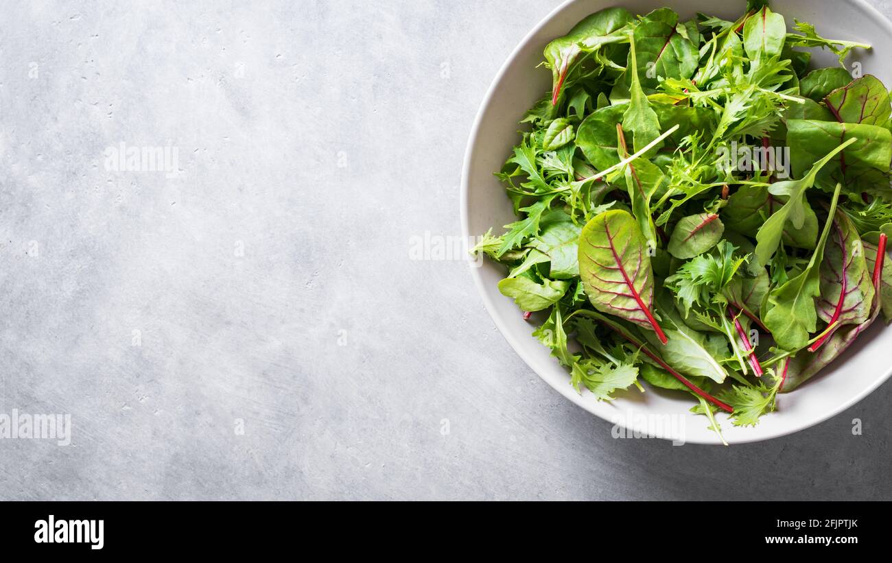 Insalata verde sana, foglie biologiche fresche mescolano insalata con rucola, bietola svizzera e lattuga, sfondo grigio chiaro, vista dall'alto, spazio copia. Foto Stock