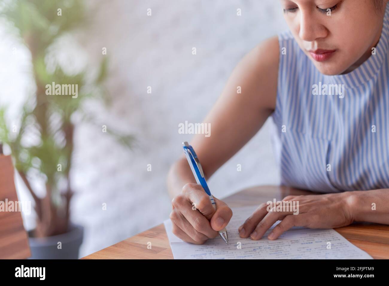 Le donne di affari usano carta di documento di scrittura della penna. Mano femminile primo piano con una penna blu su un foglio bianco. Donna scrive informazioni su un pezzo di p Foto Stock