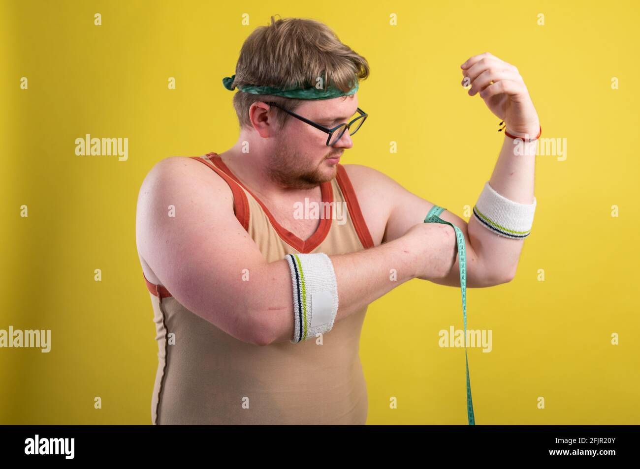 un uomo in abbigliamento sportivo misura il suo volume corporeo. Concetto di stile di vita sano, cibo sano Foto Stock