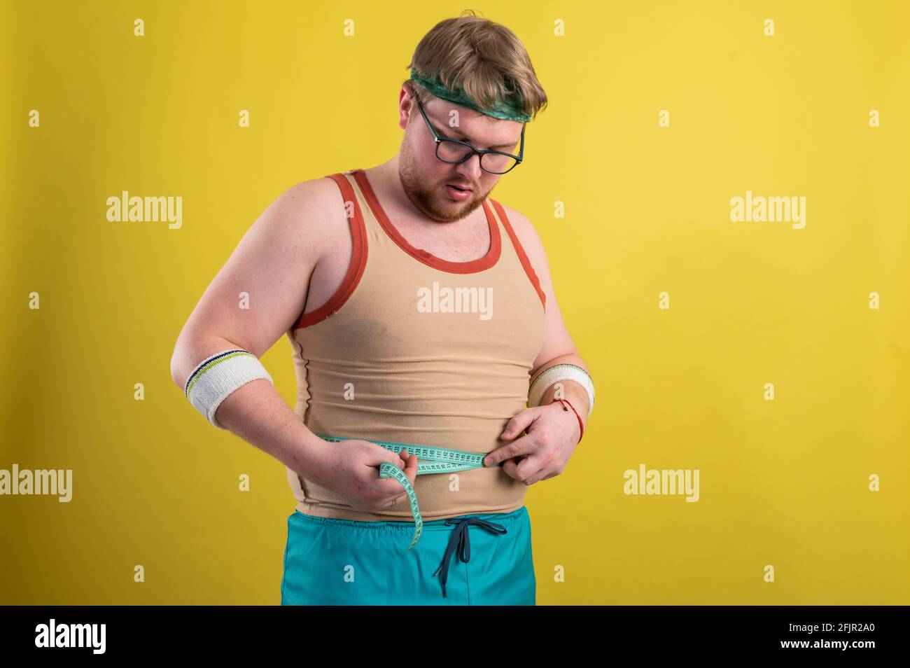 un uomo in abbigliamento sportivo misura il suo volume corporeo. Concetto di stile di vita sano, cibo sano Foto Stock