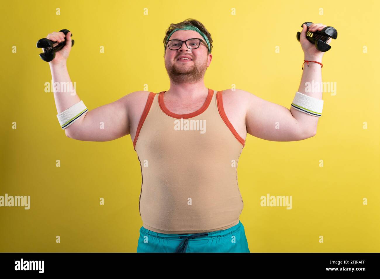 divertente uomo grasso va in per lo sport. Fa un esercizio di bicipiti di manubri Foto Stock