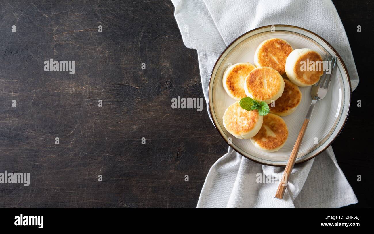 Frittelle di formaggio cottage. Cheesecakes dal formaggio di cottage, deliziosa colazione, tradizionali frittelle dolci russe. Con mirtillo, menta e miele. Foto Stock