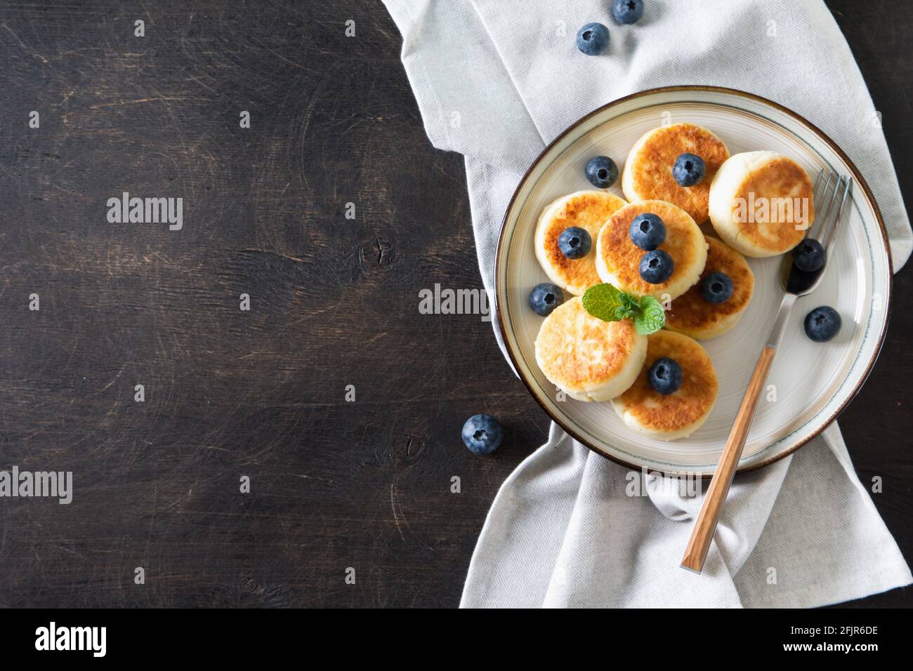Frittelle di formaggio cottage. Cheesecakes dal formaggio di cottage, deliziosa colazione, tradizionali frittelle dolci russe. Con mirtillo, menta e miele. Foto Stock