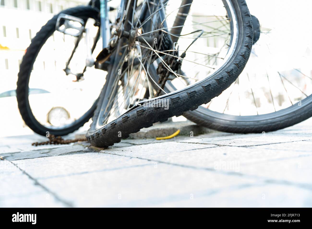 Il pneumatico posteriore piegato di una bicicletta in città con catena distrutta. Foto Stock