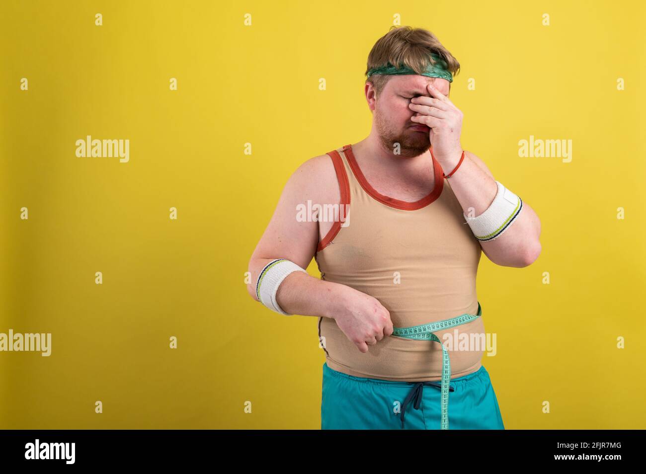 divertente uomo grasso in sportswear prende le misure del volume del corpo Foto Stock