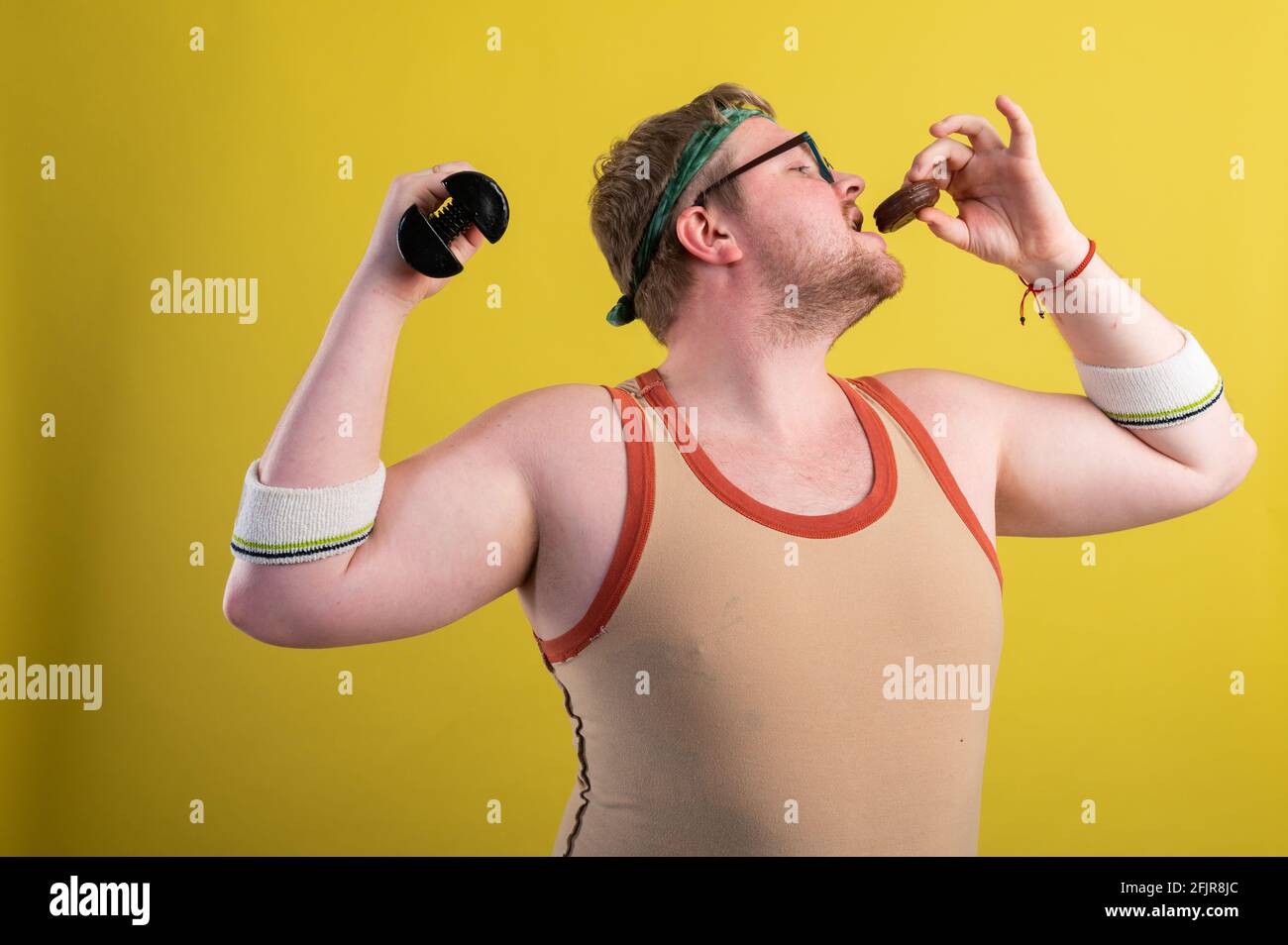 Divertente uomo sovrappeso flettendo il suo muscolo isolato su sfondo giallo Foto Stock