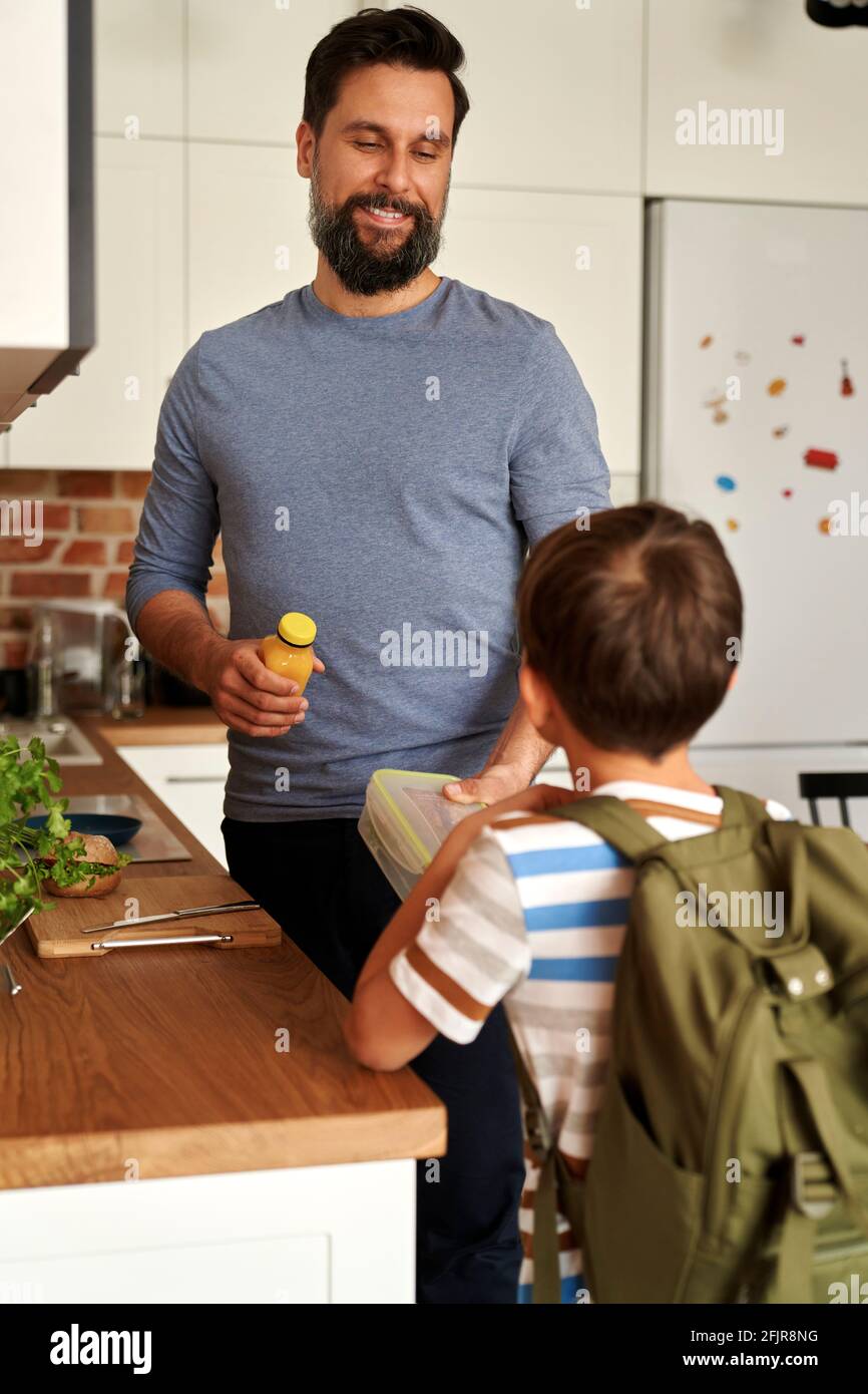 Padre che dà il suo figlio pranzo scatola con cibo sano Foto Stock