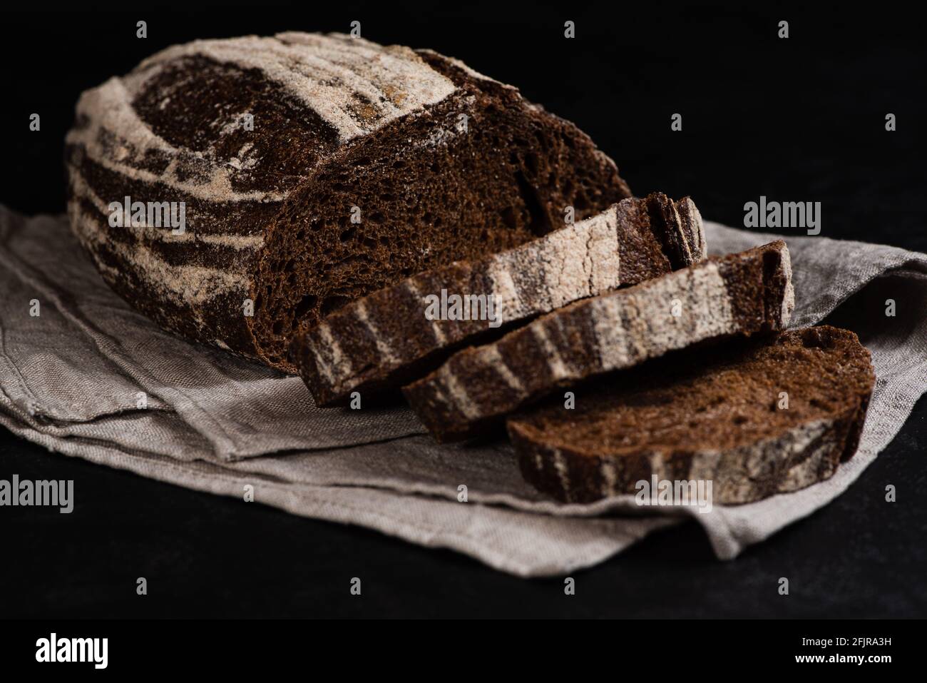 Pane artigianale di segale a fette. Primo piano di fette di pane appena sfornato su fondo scuro. Tasto basso. Messa a fuoco selettiva Foto Stock