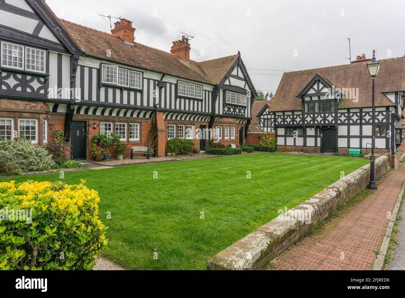 Attraenti case Tudor in mattoni rossi e mezze travi in legno costruite intorno ad un giardino comune nel villaggio di Thornton Hough, Wirral, Regno Unito Foto Stock