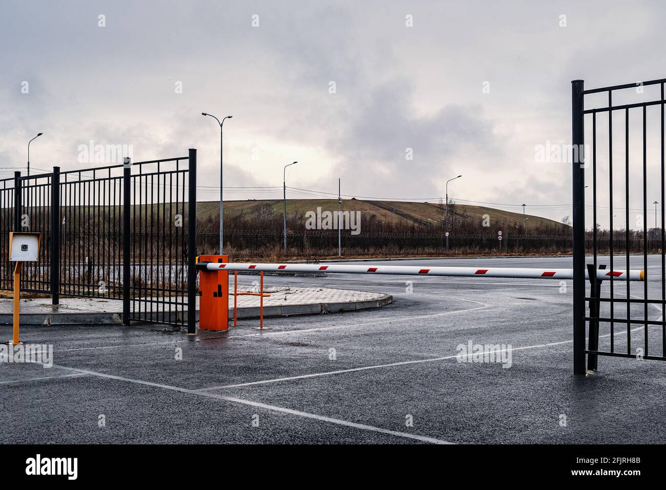 Barriera automatica di colore arancione con striscia bianca e strisce rosse di segnalazione, per l'ingresso delle vetture. Ingresso al parcheggio della fabbrica di automobili Foto Stock
