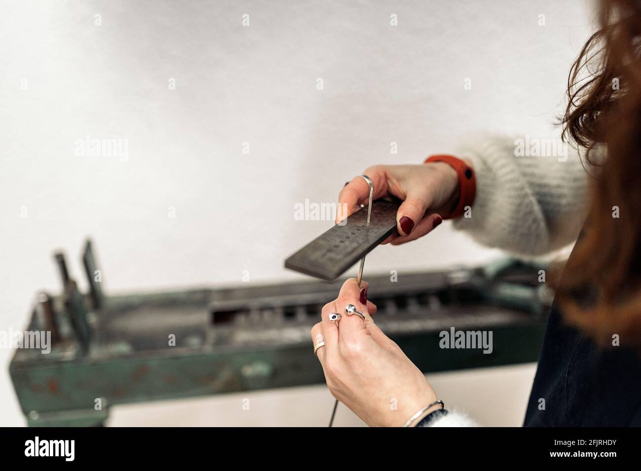 Artigiana non riconosciuta che lavora e utilizza una macchina speciale in un'officina di gioielleria. Foto Stock