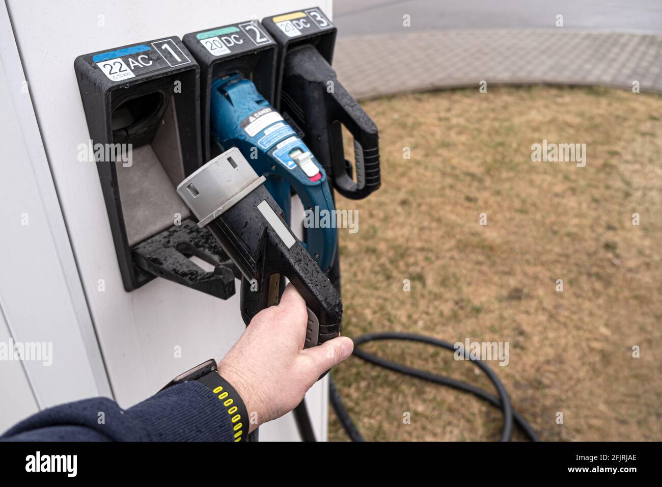 Stazione di gas elettrica per veicoli elettrici. L'uomo prende il filo di contatto per collegare la macchina Foto Stock