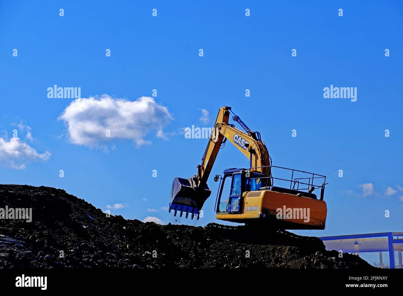 Digger meccanico su un tumulo contro il cielo blu su a. cantiere Foto Stock