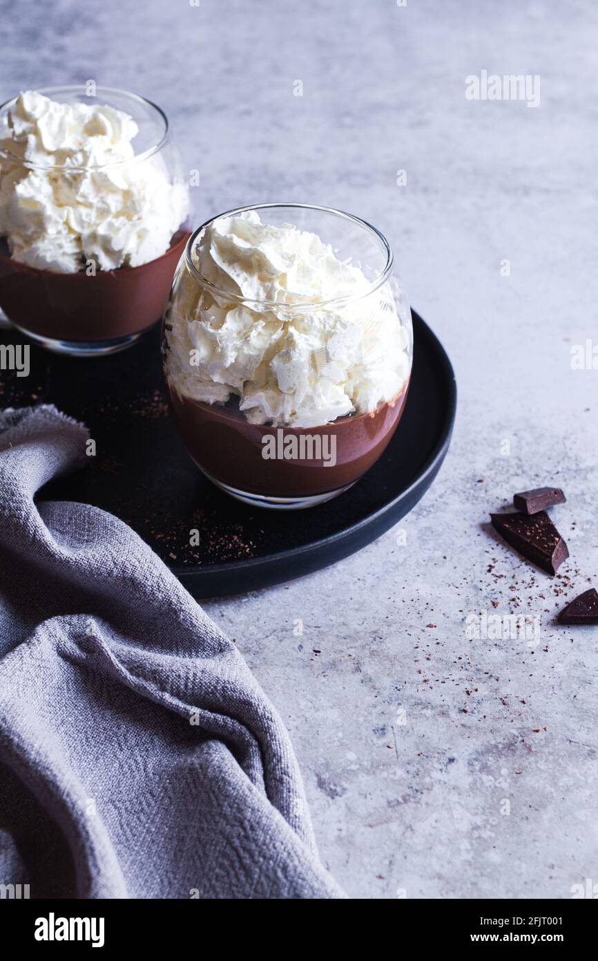 Due tazze di budino di cioccolato liegeois ricoperte di panna montata. Foto Stock
